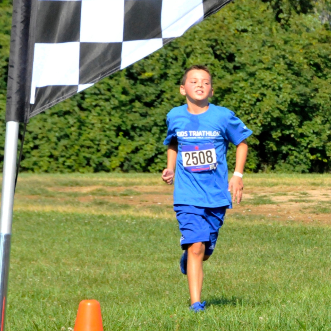 a child racer running through the grass past a checkered flag and a traffic cone